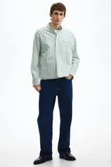 Camisa de manga larga de algodón Oxford con patrón de rayas verticales en color verde y blanco, cuello americano, cierre frontal de botones y un bolsillo aplicado en el pecho.