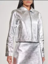 Chaqueta corta plateada de cuero sintético con cuello clásico, cierre frontal con cremallera y bolsillos laterales con cremallera.
