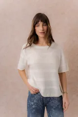Sweater tejido celeste de manga corta con textura y delicadas líneas horizontales en relieve. Presenta cuello redondo y calce amplio con hombros caídos.