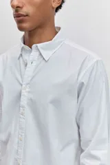 Camisa de manga larga en color celeste con estampado de rayas verticales finas, cuello abotonado y cierre frontal con botones.