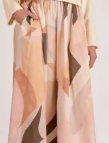 Falda larga de tiro alto con cintura elastizada y bolsillos laterales, con diseño estampado de formas abstractas en tonos cálidos y neutros.