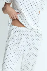 Pijama de dos piezas compuesto por una remera de manga corta con cuello redondo y un pantalón largo de corte recto, ambos con estampado de lunares pequeños.