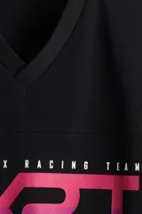 Remera de malla negra con cuello en V, mangas cortas y hombros caídos. Presenta un estampado frontal con la frase "THUNDER X RACING TEAM" y un diseño gráfico en tonos rosa, azul y celeste con la palabra "RACING" y un patrón de cuadros.