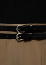 Vestido corto de diseño combinado con cuerpo de tejido de punto negro de cuello alto y manga larga, y falda evasé color tostado con tablas y trabillas. Incluye cinturones decorativos negros con hebillas metálicas.