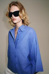 Camisa de mezcla de algodón de corte oversize y diseño asimétrico en tono azul, con cuello solapa, mangas tipo kimono por debajo del codo y cierre lateral con botones.