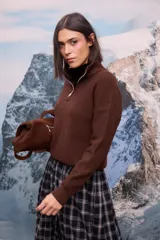 Buzo de tejido extra suave en color blanco, con cuello alto y cierre frontal parcial. Presenta mangas largas con puños ajustados y diseño de corte holgado.