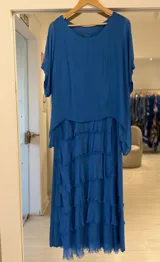 Vestido midi azul francia de gasa con múltiples volados horizontales deshilachados en la falda y capa superior superpuesta de mangas cortas.