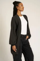 Cárdigan negro de tejido de punto con diseño holgado, cuello y puños acanalados, bolsillos laterales y mangas largas abullonadas.