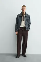 Pantalón de hombre color marrón oscuro, de corte balloon fit, con cintura con trabillas y cierre frontal de botón y cremallera. Presenta bolsillos delanteros y bolsillos traseros de vivo.