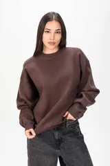Sweater de punto color marrón, de corte oversize, con cuello redondo y mangas largas con puños ajustados.