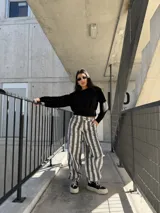 Pantalón de jean con diseño de rayas verticales en tonos gris y blanco, de corte ancho y relajado.