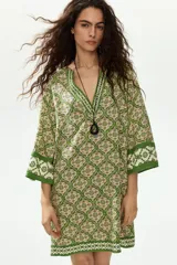 Vestido túnica corto de viscosa con estampado geométrico en tonos verdes y crudo, escote en V pronunciado tanto en el frente como en la espalda, mangas tres cuartos y diseño oversized.