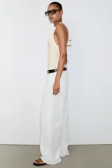 Body de cuello halter con espalda descubierta, confeccionado en poliamida. Presenta un diseño drapeado en los laterales y una abertura frontal con detalle metálico. Posee cierre con botones a presión en la parte inferior y lazada en el cuello.