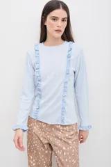 Remera de manga larga color blanco, con diseño de volados verticales en el frente y en los puños. Confeccionada en tejido suave y confortable, con un calce cómodo y favorecedor.
