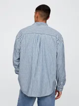 Camisa de jean de manga larga con estampado de rayas verticales en tonos azul y blanco. Presenta cuello clásico, cierre frontal con botones y un bolsillo en el pecho.