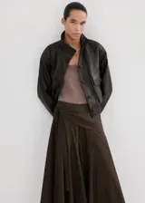Falda larga color marrón oscuro, con diseño evasé, tiro medio y detalle cruzado tipo pañuelo con cierre de nudo en la cintura.