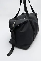 Bolso tipo duffel negro de símil cuero con cierre superior de cremallera metálica y asas reforzadas.