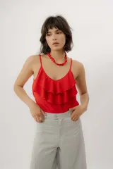 Musculosa negra con escote en V, breteles finos regulables y doble volado frontal con pespuntes.
