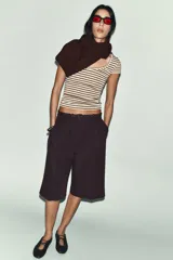 Camiseta de corte ajustado con escote redondo y manga corta, confeccionada en tejido de punto con lana. Presenta un diseño de rayas horizontales en tonos beige y marrón.