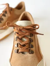 Zapatillas deportivas de cuero color camel con cordones marrones y suela blanca.