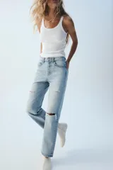 Jeans wide leg de tiro alto y cinco bolsillos, confeccionados en denim con lavado azul medio y efecto desgastado. Presenta cierre frontal con cremallera y botón metálico.