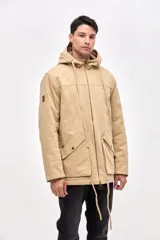 Campera tipo parka de gabardina color beige, con capucha ajustable, cierre frontal y bolsillos laterales con solapa. Presenta un diseño clásico con interior capitoneado.