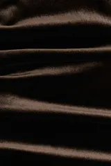 Vestido largo sin mangas confeccionado en velour suave. Presenta un diseño entallado con cuello alto y un efecto drapeado creado mediante pliegues estratégicos en el hombro y en el lateral de la cintura.