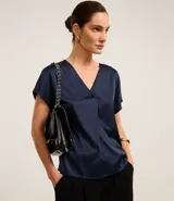 Blusa azul marino de poliéster y elastano con acabado satinado, escote en V, mangas cortas y pliegues delanteros.