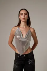 Top halter plateado de malla metálica con escote buche y tirantes de cadena fina.