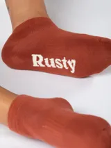 Medias cortas celestes con el nombre de la marca Rusty estampado en azul en la planta del pie.