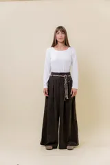 Pantalón wide leg de tiro alto en color negro, con diseño de pinzas delanteras que aportan volumen y caída fluida. Incluye bolsillos laterales y un lazo desmontable en la cintura que combina cordón con cinta de estampado animal print.