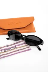 Lentes de sol Lemon de armazón ovalado color negro y cristales oscuros, con detalle de la marca en letras doradas en la patilla.