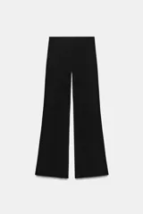 Pantalón largo negro de tiro alto, confeccionado en tejido elástico, con cintura elástica y diseño de pierna ancha tipo palazzo con bajo evasé.