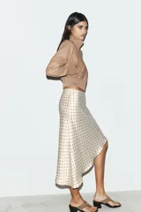 Falda midi de tejido satinado con estampado de lunares, tiro medio, cintura elástica y bajo asimétrico.