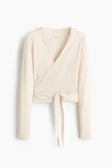 Top deportivo cruzado de modal suave, en color beige claro, con escote en V pronunciado, mangas largas y tiras para anudar en la cintura.