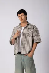 Camisa de manga corta de poplín a cuadros, con calce boxy, cuello camisero, cierre frontal de botones y un bolsillo en el pecho con detalle de bordado.