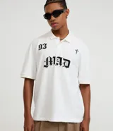 Remera boxy de algodón color blanco, con cuello polo y diseño de letras y cruz estampadas en el frente.