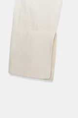 Camisa corta de manga larga con cuello solapa, confeccionada en tejido con efecto arrugado. Presenta cierre frontal con botones y forro interior combinado con tejido semitransparente.