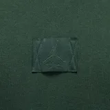 Buzo canguro con capucha de la línea Jordan Flight Fleece, color verde oscuro. Presenta un diseño minimalista con bolsillo frontal tipo canguro, cordones ajustables en la capucha y un parche tonal con el logo Jumpman en el centro del pecho.