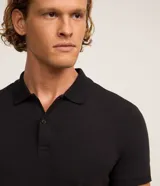 Remera polo slim negra de algodón con textura acanalada, cuello clásico con botones y mangas cortas.