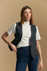 Chaleco sastrero de corte entallado con estampado de cuadros en tonos beige, marrón y azul. Presenta escote en V, cierre frontal con botones y terminación en punta en el ruedo. Incluye ajuste con hebilla en la espalda.
