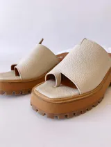 Sandalias de cuero crudo con tira ancha sobre los dedos y suela track color caramelo.