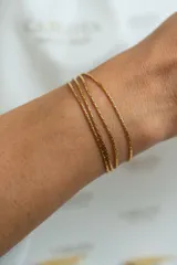 Pulsera dorada de acero quirúrgico con cuatro cadenas finas y cierre de mosquetón con cadena de alargue.