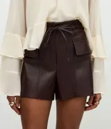 Short de tiro alto confeccionado en poliuretano con acabado brillante, presenta bolsillos delanteros con solapas estructuradas y cintura con elástico posterior. Incluye un cinto fino del mismo material para ajustar en la cintura.