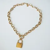 Collar corto dorado con eslabones gruesos y dije de candado.