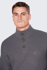 Buzo gris de tejido grueso con cuello alto y medio cierre con botones.