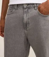 Pantalon de jean gris con lavado deslavado, de corte baggy y silueta holgada. Cuenta con bolsillos al frente y atras, y cierre de boton y cremallera.
