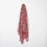 Pashmina rectangular de color rojo con estampado cachemir en tonos beige y borlas rojas en los extremos.