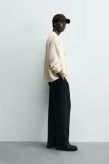 Cárdigan de punto color crema, con cuello pico, manga larga y cierre frontal de botones marrones. Presenta un calce relajado y acabados en rib.