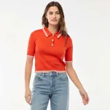 Sweater de punto canalé color naranja, de manga corta, con cuello polo blanco y ribetes a rayas blancas en el cuello, puños y dobladillo. Presenta cierre frontal con botones dorados.